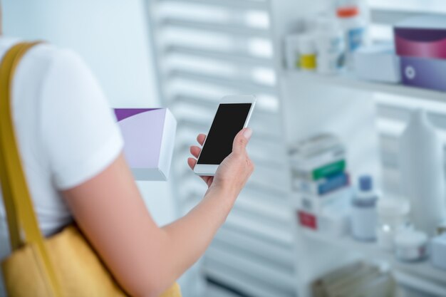 Foto cerca de una mujer eligiendo medicamentos y buscando información en línea