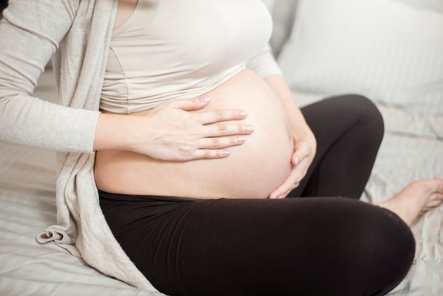 Cerca de la mujer embarazada aplicar crema en su vientre