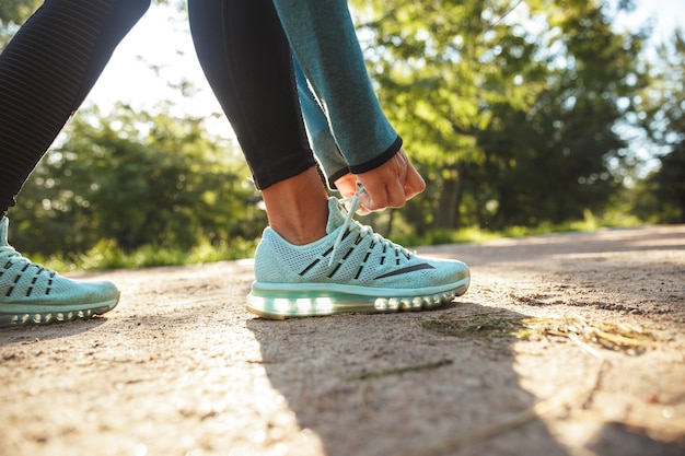 Cerca de una mujer fitness atar sus cordones al aire libre