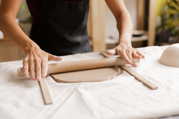 Cerca de una mujer haciendo vajillas de cerámica y alfarería en el taller, trabajando con arcilla