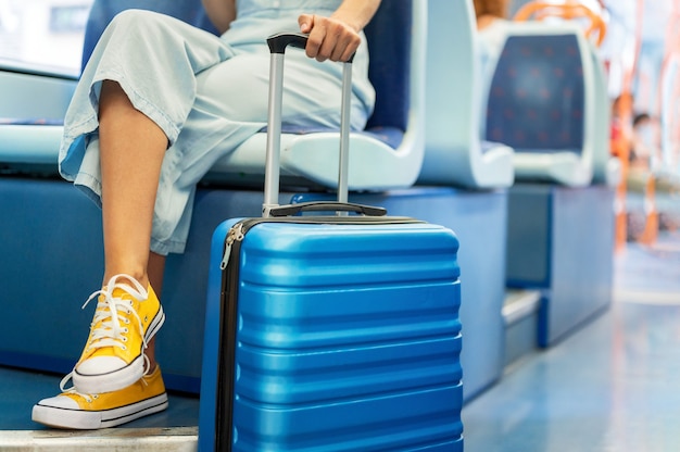 Cerca de una mujer irreconocible que lleva una maleta, viajando en tren.