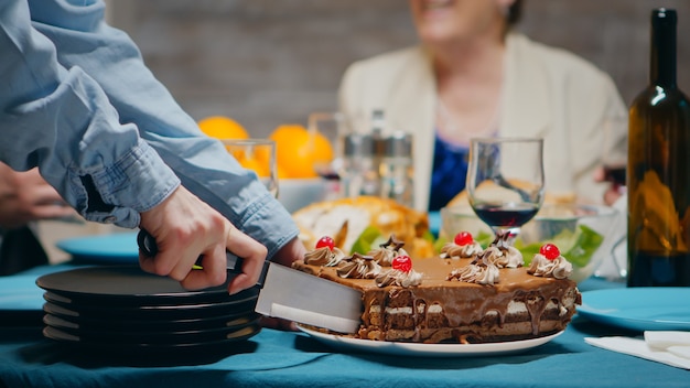 Cerca de una mujer joven cortando un delicioso pastel en su cumpleaños para la familia.