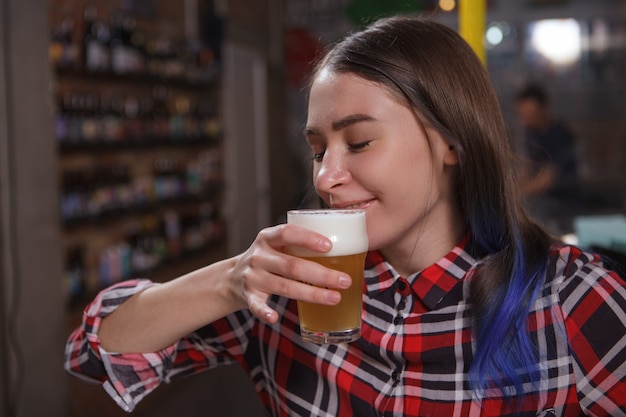 Cerca de una mujer joven disfrutando de una deliciosa cerveza en el pub, espacio de copia