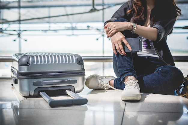 Foto cerca de la mujer joven con maleta de bolsa y maleta esperando para la salida