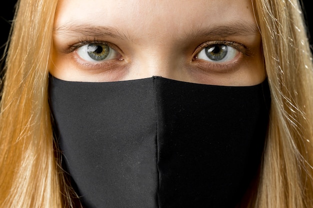 Foto cerca de una mujer joven con mascarilla negra. concepto de período de cuarentena de coronavirus pandémico covid-19.