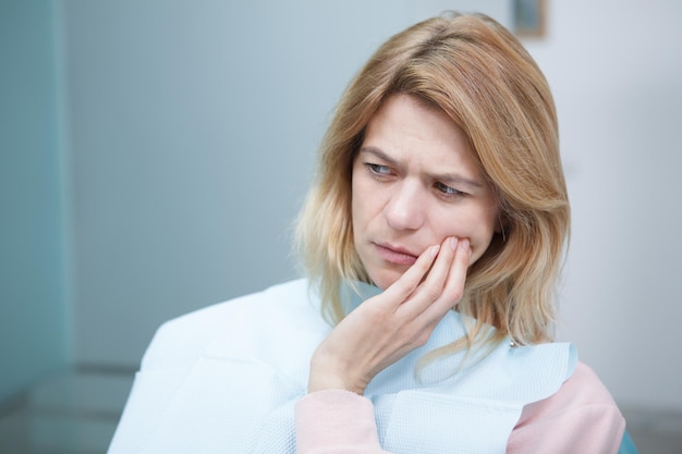 Cerca de mujer madura con dolor de muelas en la oficina de dentistas