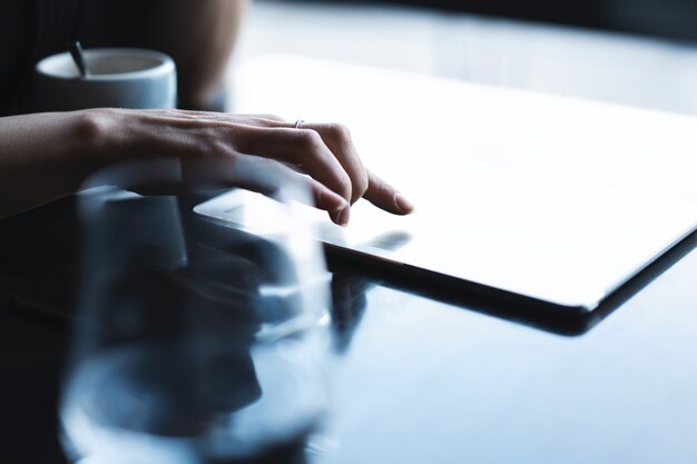 Cerca de la mujer de las manos con su tablet pc en restaurante, cafetería.