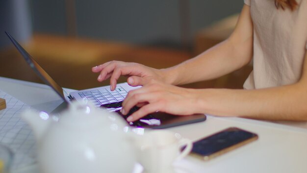 Foto cerca de una mujer de negocios sonriente escribiendo en el teclado de la computadora portátil en la oficina de casa chica alegre charlando en una computadora portátil en casa profesional femenina trabajando en una computadora portátil en la cocina doméstica