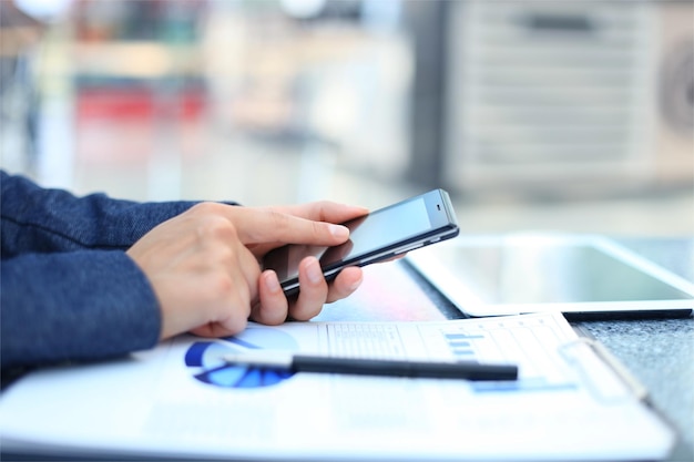 Cerca de una mujer de negocios mediante teléfonos móviles inteligentes