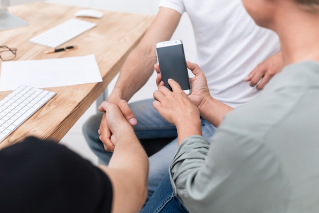 De cerca. una mujer de negocios utiliza un teléfono inteligente en una reunión de socios comerciales. personas y tecnologia