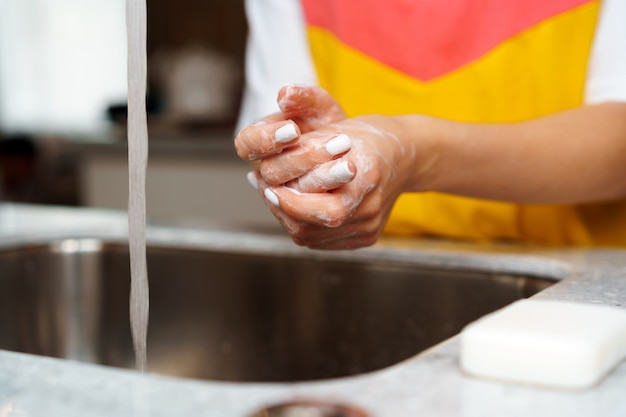 Foto cerca de una mujer que se lava las manos en el fregadero de la cocina