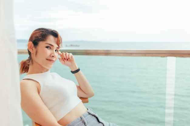 Cerca de la mujer relajarse en el balcón del hotel con vistas al mar en verano