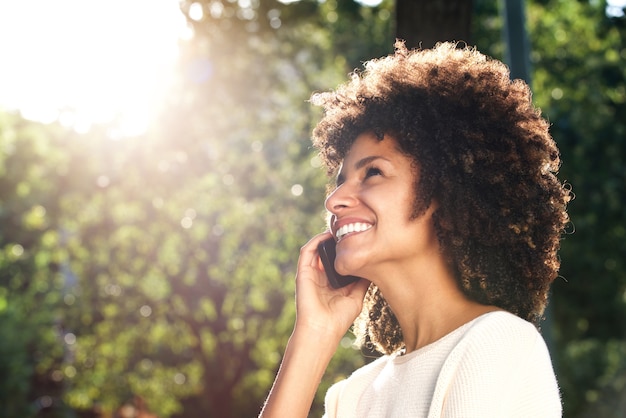 Cerca mujer sonriente hablando por teléfono móvil en el parque