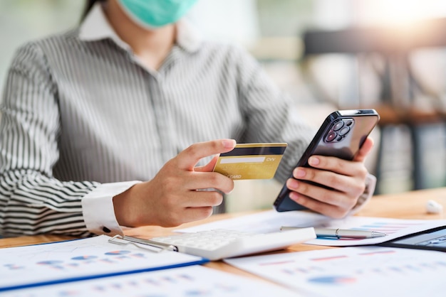 De cerca. mujer con teléfono inteligente y usando tarjeta de crédito para compras en línea.