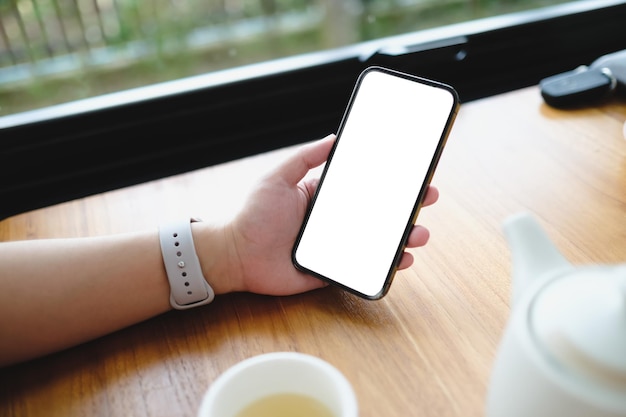 Cerca de una mujer usando un teléfono celular, enviando masajes en la cafetería con pantalla negra, enviando mensajes de texto, videollamadas.