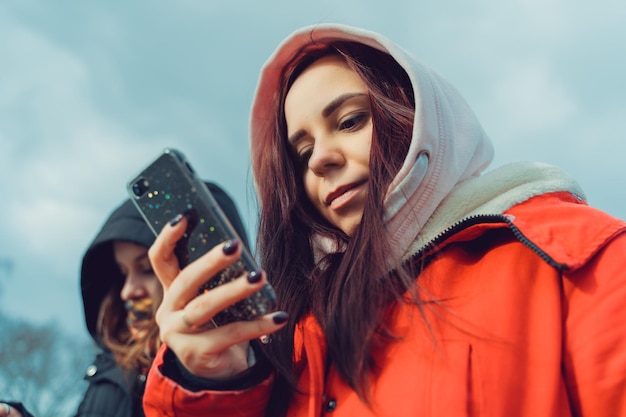 Cerca de mujeres jóvenes navegando por teléfono inteligente en el parque de la ciudad