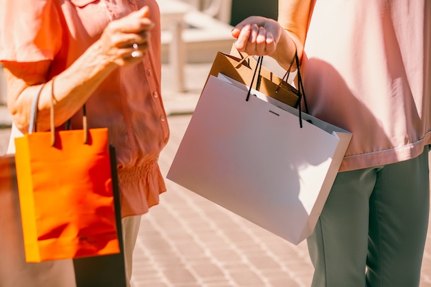 Cerca de mujeres que llevaban bolsas de papel de colores en el día de compras