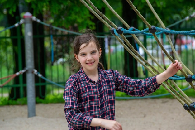 Cerca de una niña feliz jugando y sentada en el columpio en el parque natural