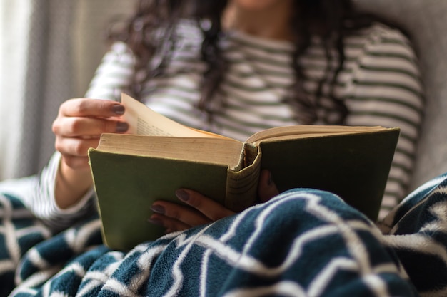 Foto cerca de una niña feliz está leyendo un libro en su sala de estar