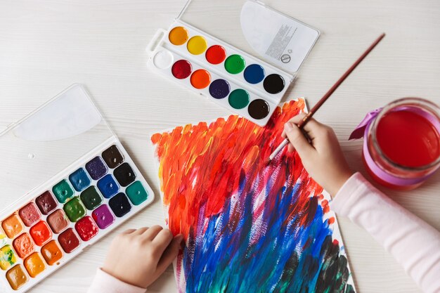 Cerca de una niña pintando un cuadro sobre una mesa