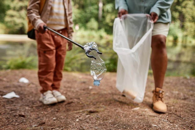 Cerca de una niña recogiendo una botella de plástico al aire libre ayudando a limpiar la naturaleza