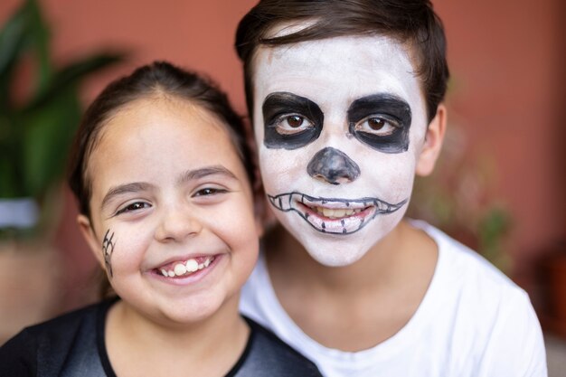 Cerca de niño caucásico y niño pequeño con maquillaje para fiesta de Halloween. Ellos están sonriendo.