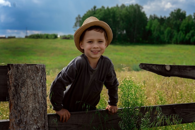 Cerca de niño con sombrero sentado en la valla