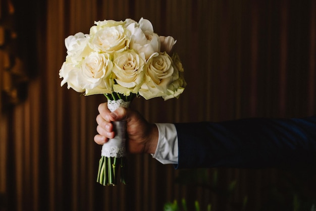 Cerca del novio con ramo de flores en el apartamento antes de la boda