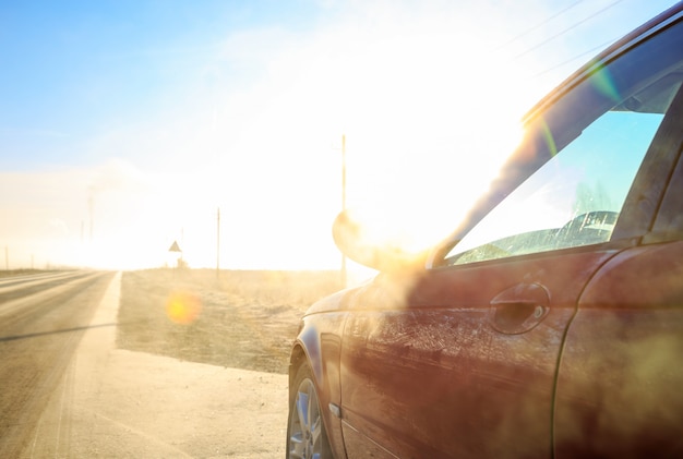 Cerca del nuevo coche rojo en la carretera de asfalto en un día soleado