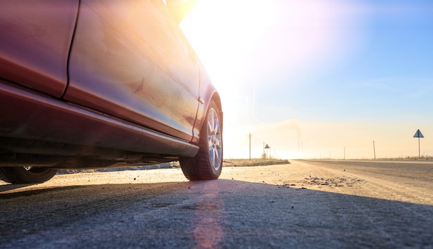 Cerca del nuevo coche rojo en la carretera de asfalto en un día soleado