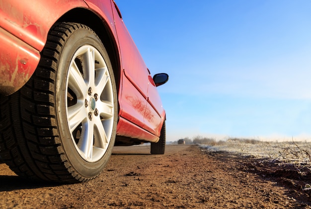 Cerca del nuevo coche rojo en la carretera de asfalto en un día soleado