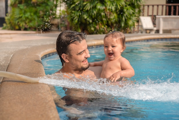 Cerca de padre con bebé en la piscina