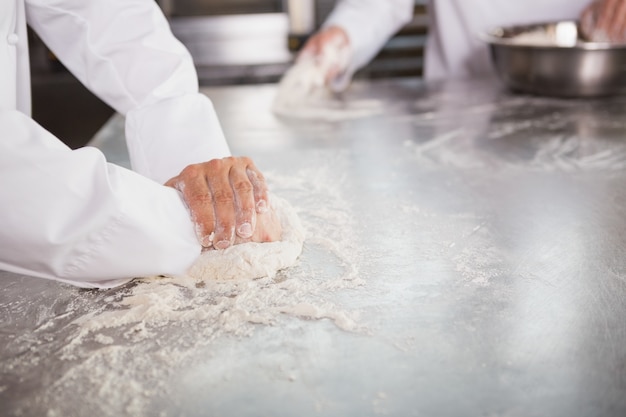 Cerca de los panaderos amasando la masa en el mostrador