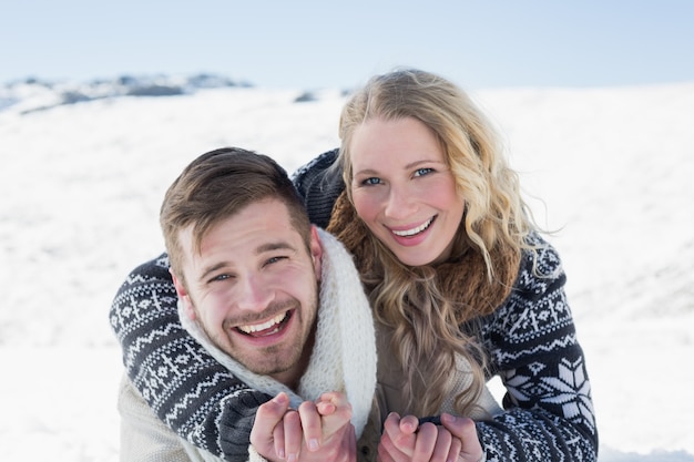 Cerca de una pareja alegre cogidos de la mano en la nieve