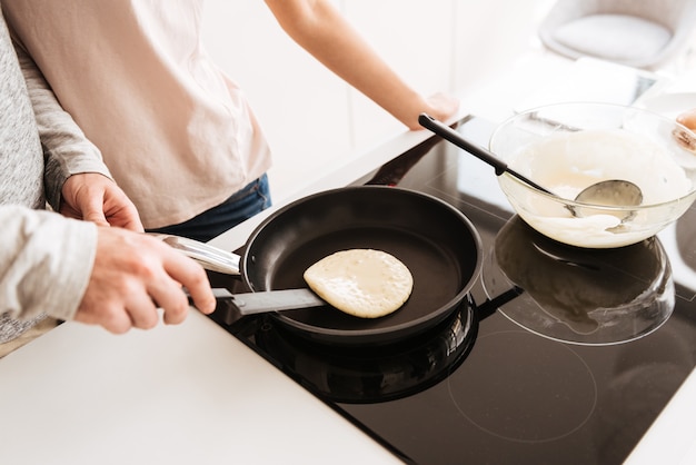 Cerca de una pareja cocinando panqueques