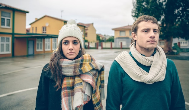 Cerca de la pareja vistiendo ropa de invierno de pie al aire libre en un día frío y lluvioso