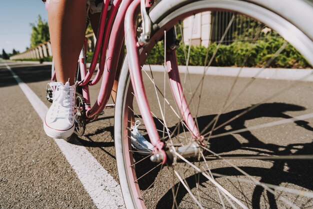 De cerca. Pierna de chicas mulatas en el pedal de bicicleta en carretera.