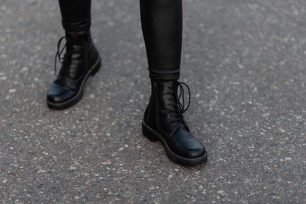 Cerca de las piernas femeninas en leggings negros de moda en elegantes botas de cuero