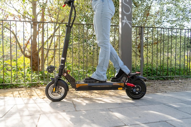 Cerca de las piernas de una niña en un scooter eléctrico en el parque