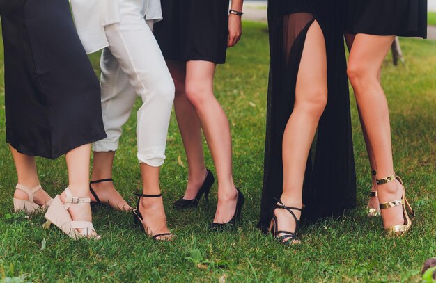 Foto cerca de los pies de la mujer en zapatos de sandalias de verano caminando sobre el césped de primavera cubierto de hierba verde fresca