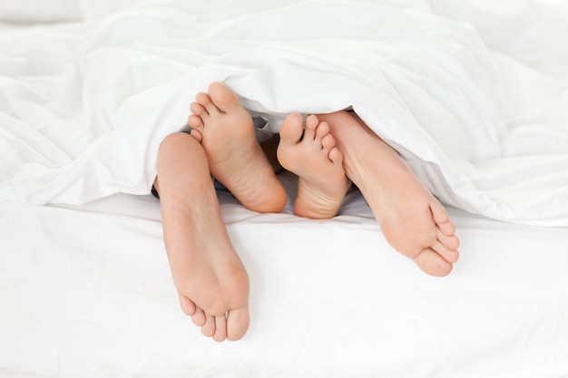 Foto cerca de los pies de la pareja mientras se divierten en su cama