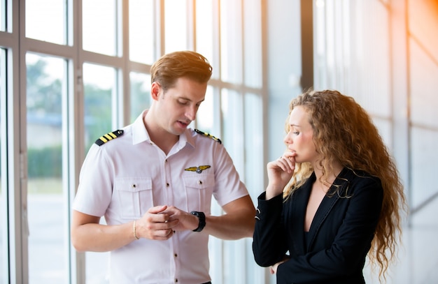 Cerca de un piloto de helicóptero masculino usar gafas de sol y empresarios o CEO ejecutivo de pie contra el helicóptero en el punto de aterrizaje de aviones en el aeropuerto en un día soleado.