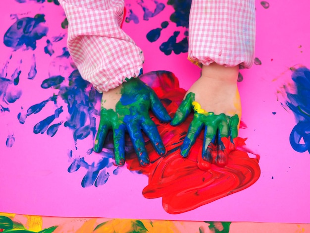 Cerca de una pintura de la mano de los niños con acuarelas de colores