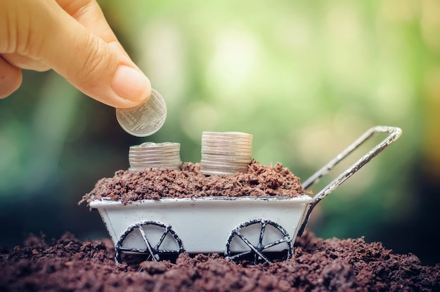 Foto cerca de poner monedas en la pila de monedas está creciendo en carretilla para inversión empresarial o concepto de ahorro