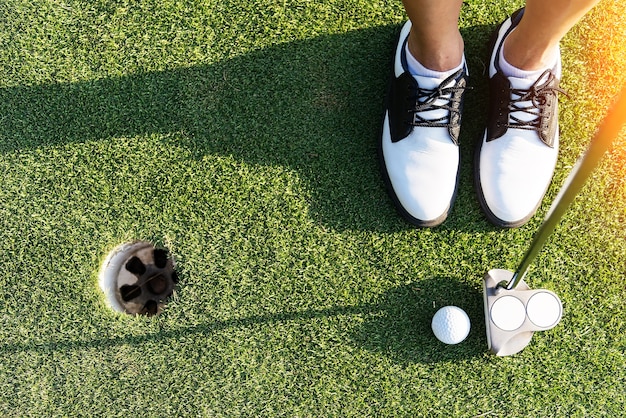 cerca de putter golpeando la pelota de golf con el agujero en el curso