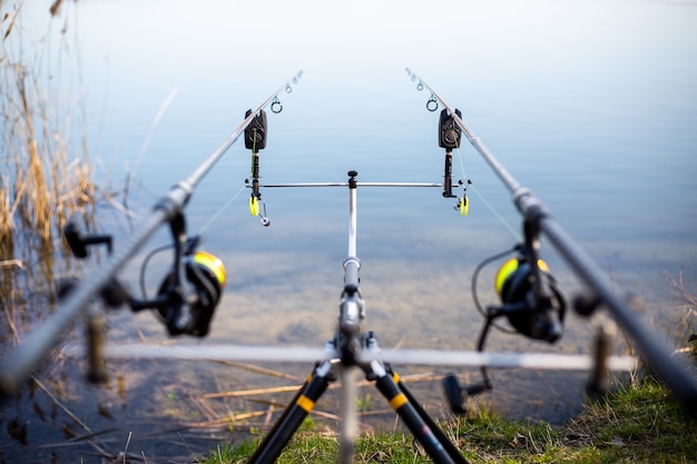 Cerca de rack con cañas de pescar en el lago, pescador esperando peces de agua dulce, pesca, deporte de pesca