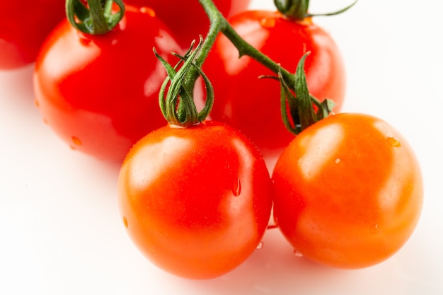 Cerca de la rama de tomates cherry sobre superficie blanca