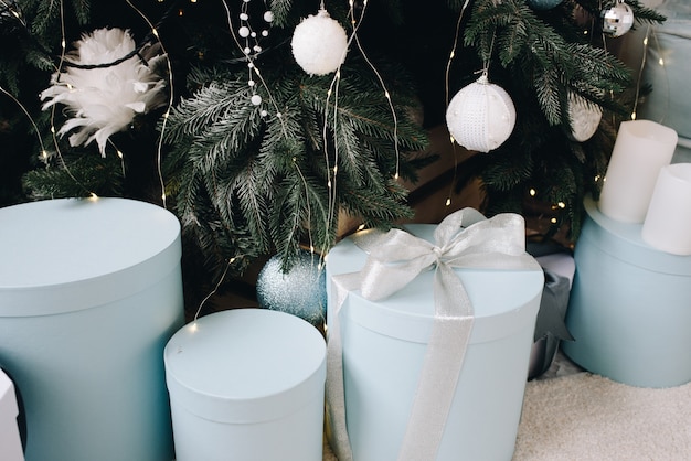 Cerca de regalos de Navidad empaquetados con estilo junto al árbol de Navidad bellamente decorado