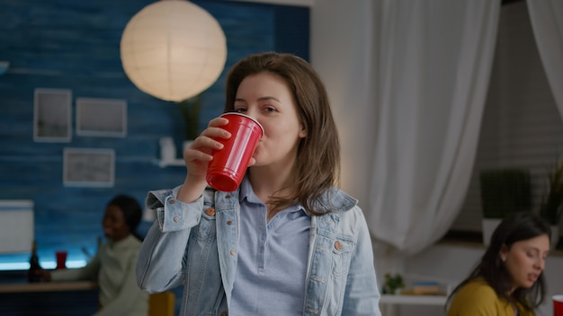 Cerca de retrato de mujer mirando a la cámara mientras bebe cerveza