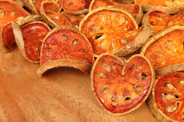 Cerca de rodajas de frutos secos de bael sobre fondo de madera.